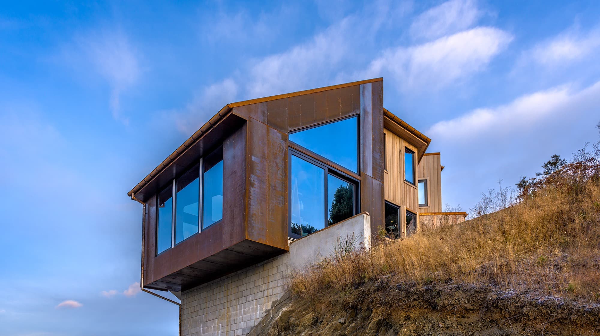 The exterior of Luc 22, corten steel and cedar cladding standing against the alpine landscape