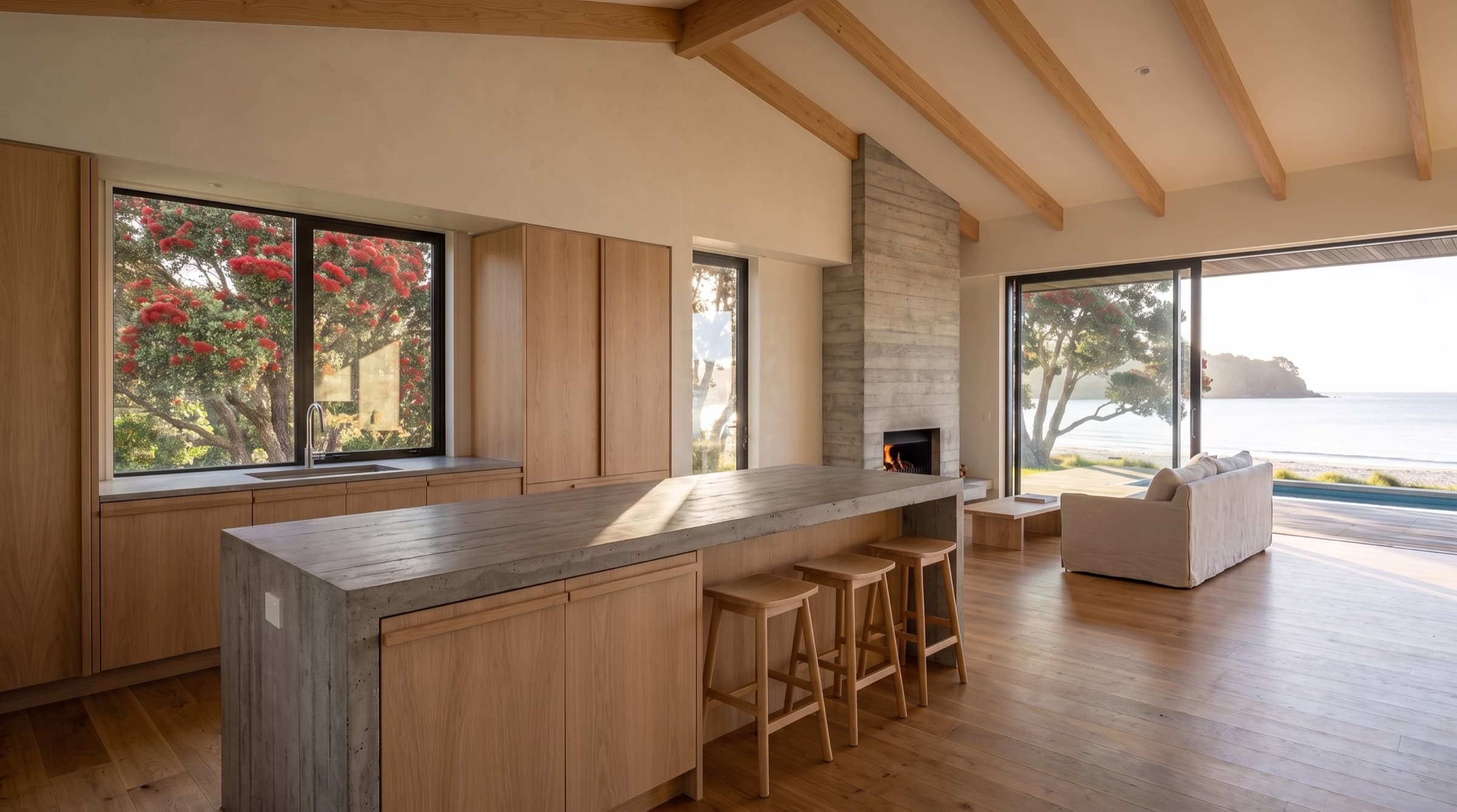 The kitchen island in board-formed concrete with oak stools and oak cabinetry behind